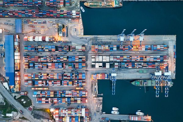 Vista aérea de un puerto de contenedores con buques de carga y grúas pórtico, aplicación del acero en construcción naval